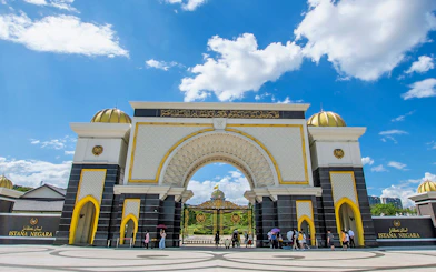 Istana Negara entrance in Kuala Lumpur with visitors and blue sky.