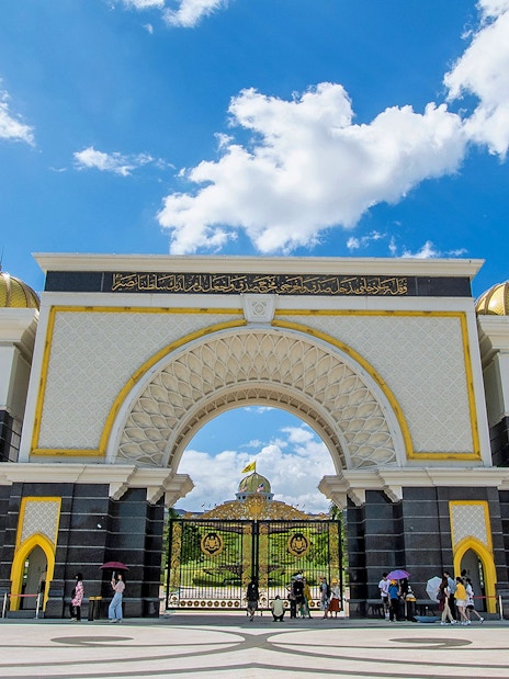 Istana Negara entrance in Kuala Lumpur with visitors and blue sky.
