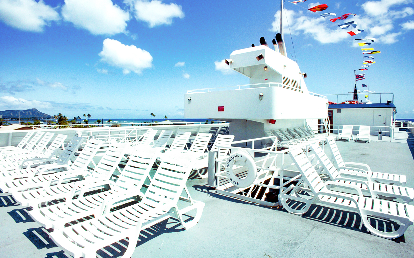 Sun loungers on cruise ship deck with ocean view in Oahu.