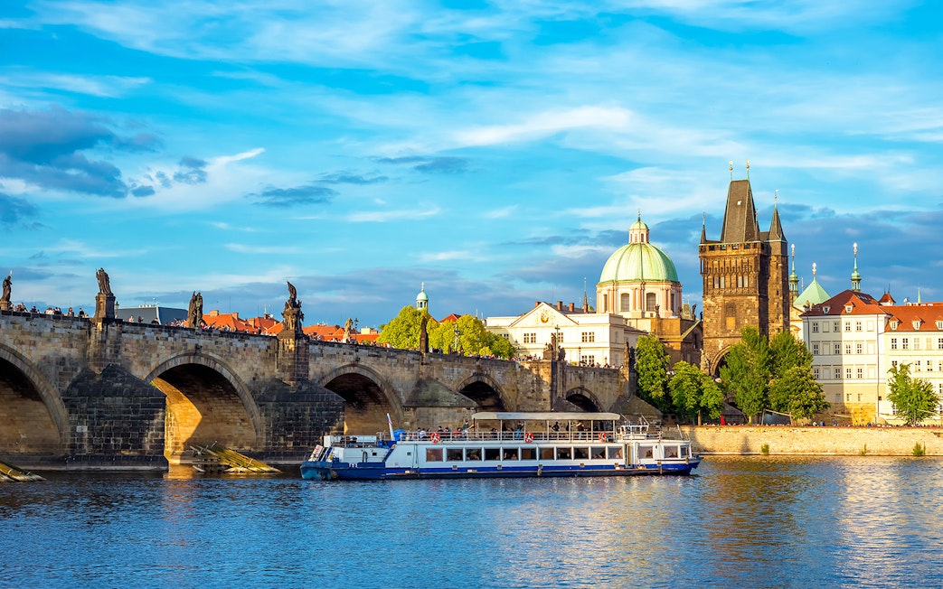 Charles Bridge and Vltava River cruise boat in Prague, Czech Republic.
