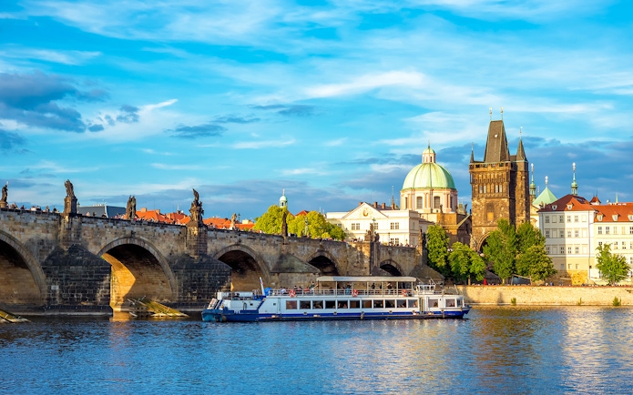 Charles Bridge and Vltava River cruise boat in Prague, Czech Republic.