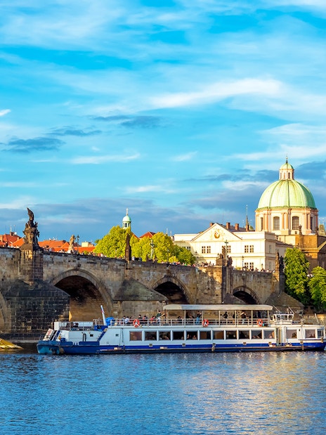 Charles Bridge and Vltava River cruise boat in Prague, Czech Republic.