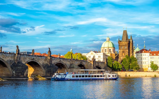 Charles Bridge and Vltava River cruise boat in Prague, Czech Republic.