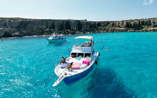 Yacht near Favignana and Levanzo Islands with swimmers in clear blue water.