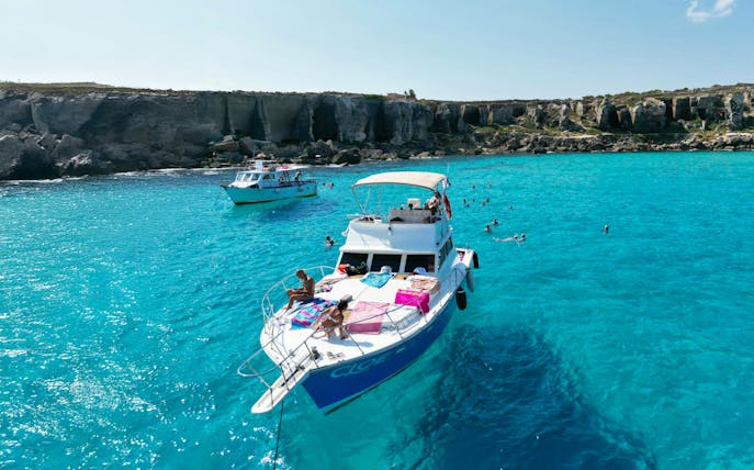 Yacht near Favignana and Levanzo Islands with swimmers in clear blue water.