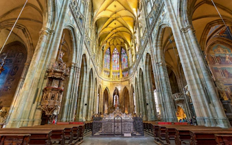 Interior of St. Vitus Cathedral at Prague Castle with stained glass windows.