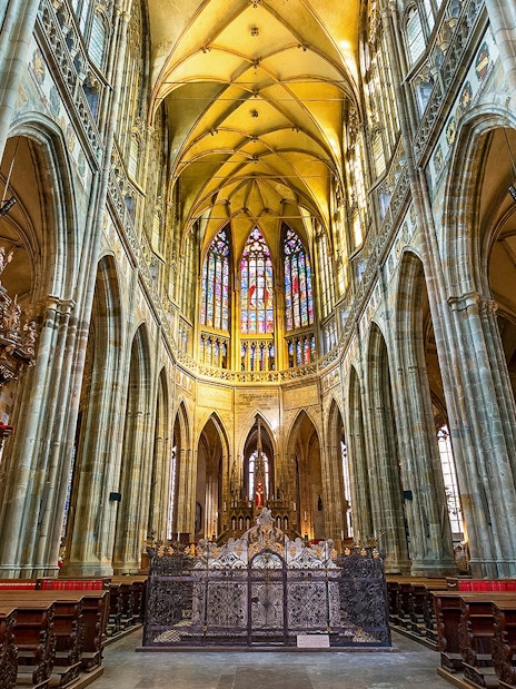 Interior of St. Vitus Cathedral at Prague Castle with stained glass windows.
