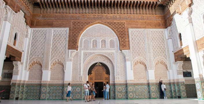 Madrasa Ben Youssef courtyard with intricate tilework and visitors exploring.