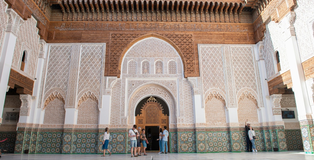 Madrasa Ben Youssef courtyard with intricate tilework and visitors exploring.
