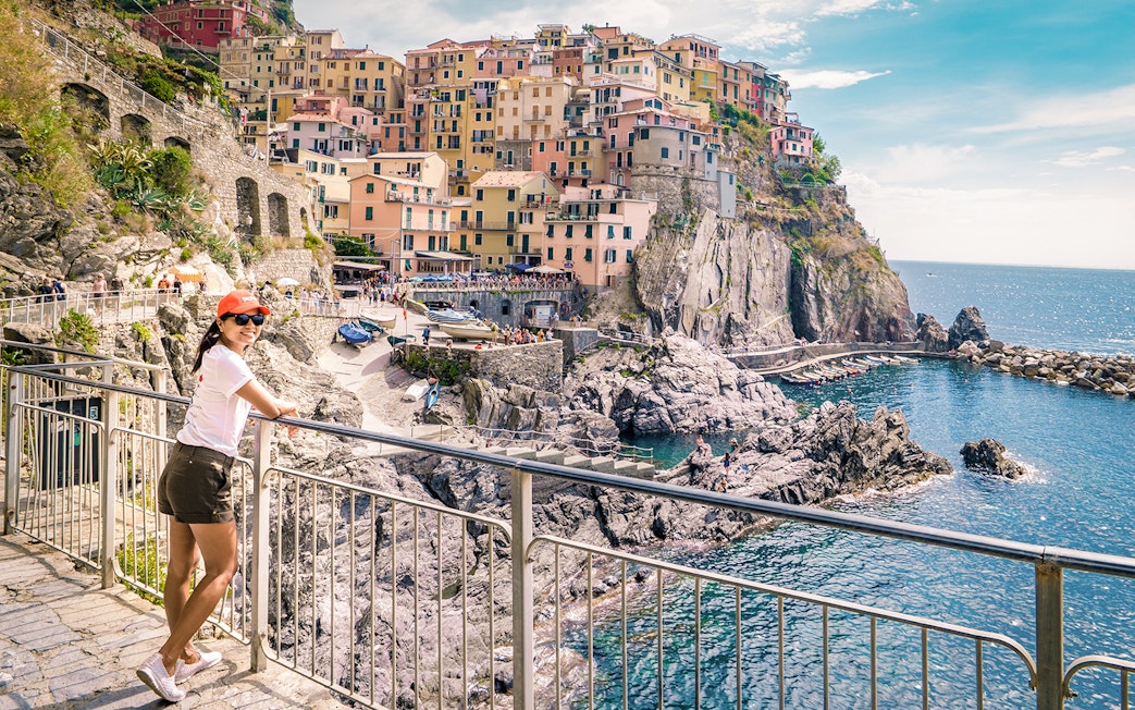 Person enjoying the view of colorful cliffside buildings in Manarola, Cinque Terre.