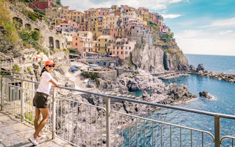 Person enjoying the view of colorful cliffside buildings in Manarola, Cinque Terre.