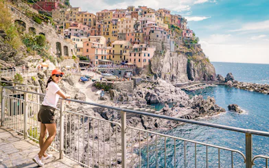 Person enjoying the view of colorful cliffside buildings in Manarola, Cinque Terre.