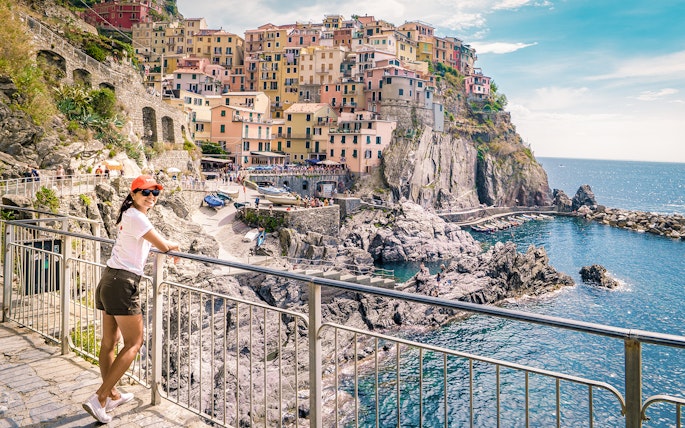 Person enjoying the view of colorful cliffside buildings in Manarola, Cinque Terre.