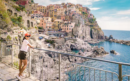 Person enjoying the view of colorful cliffside buildings in Manarola, Cinque Terre.