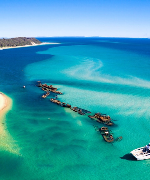 Shipwrecks and ferry near Moreton Island's coastline.