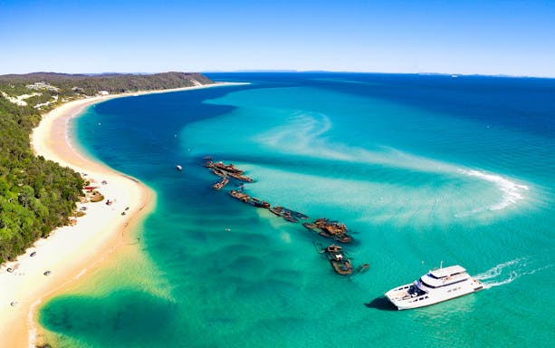 Shipwrecks and ferry near Moreton Island's coastline.