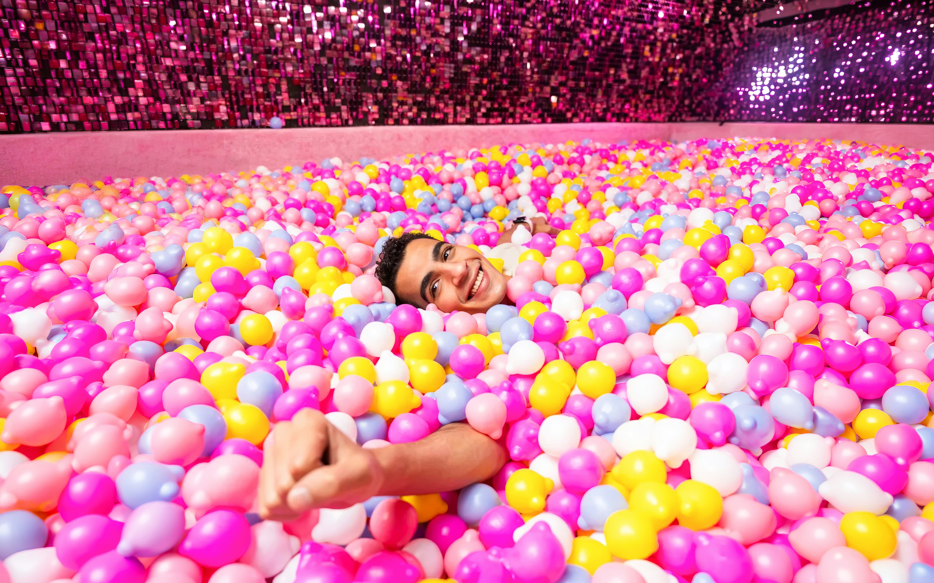 Person enjoying a colorful ball pit at Museum of Candy, Dubai.