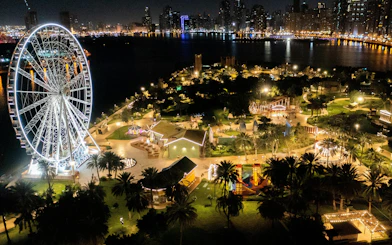 Ferris wheel and illuminated attractions at Al Montazah Parks, Island of Legends, Sharjah at night.