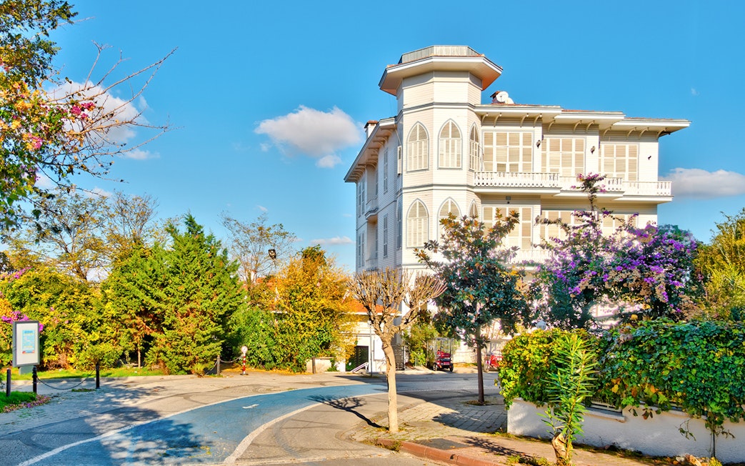 Historic mansion on Büyükada, Princes Islands, Istanbul, surrounded by lush greenery and vibrant flowers.