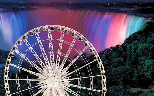 Niagara SkyWheel with illuminated Niagara Falls in the background at night.