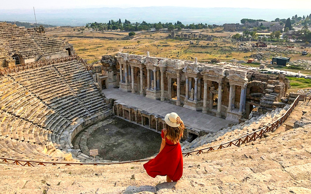 Hierapolis Amphitheatre with visitor overlooking ancient stone seats and stage, Turkey.