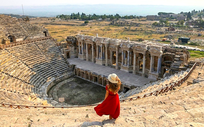 Hierapolis Amphitheatre with visitor overlooking ancient stone seats and stage, Turkey.