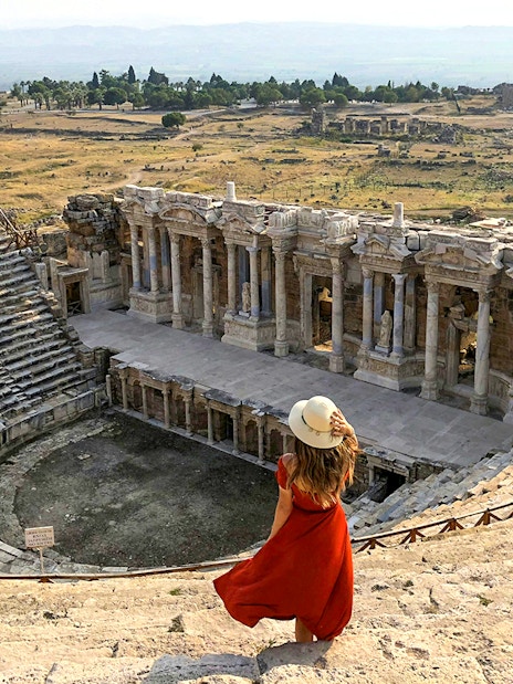 Hierapolis Amphitheatre with visitor overlooking ancient stone seats and stage, Turkey.