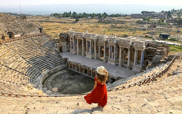 Hierapolis Amphitheatre with visitor overlooking ancient stone seats and stage, Turkey.