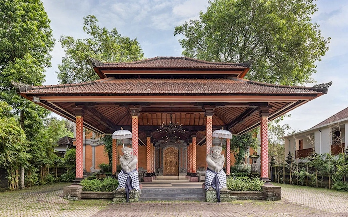 Traditional Balinese pavilion at Arma Museum Resort with guardian statues and lush greenery.