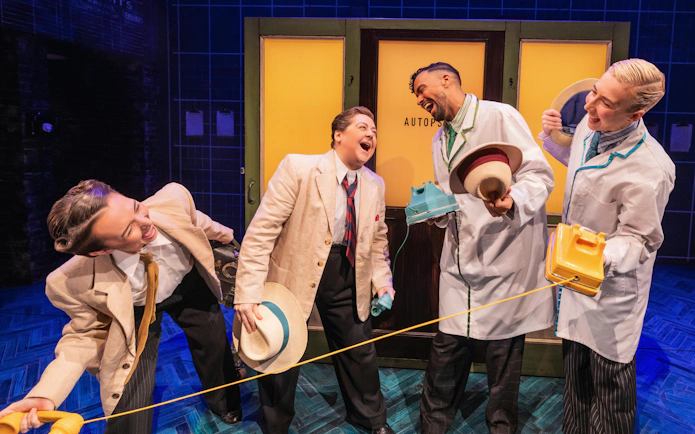 Actors in vintage attire laughing during Operation Mincemeat performance on Broadway.
