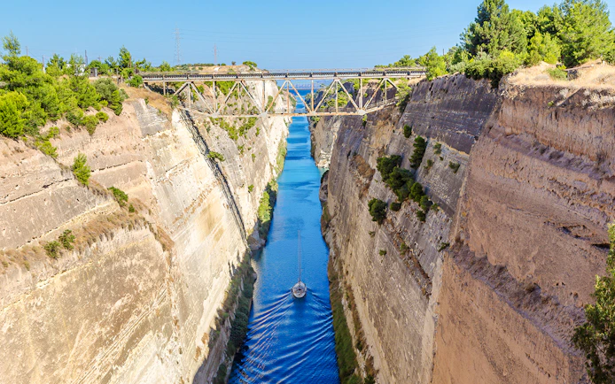 Sailboat navigating through the Corinth Canal in Ancient Olympia, Greece.