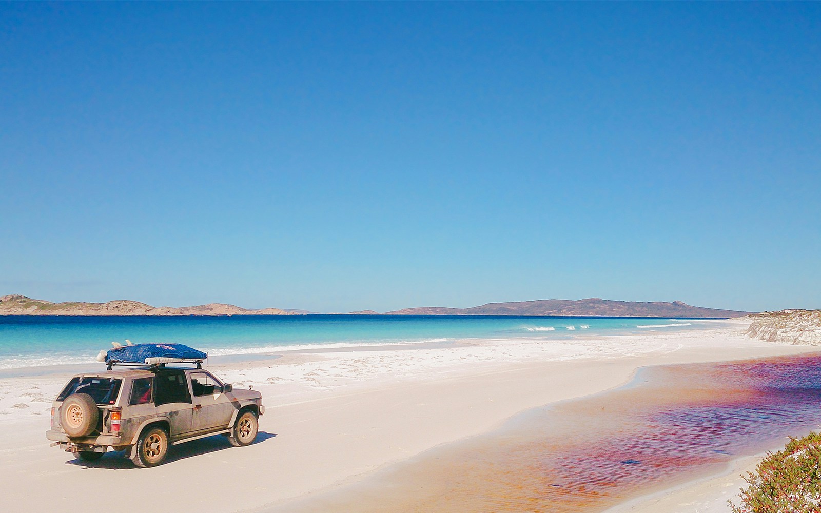 4WD vehicle on a sandy beach with ocean view, part of Noosa kayak and beach adventure tour.