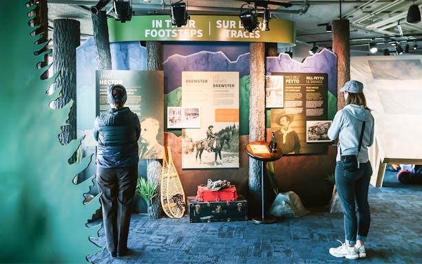 Guests reading information boards about Banff Gondola history and explorers.