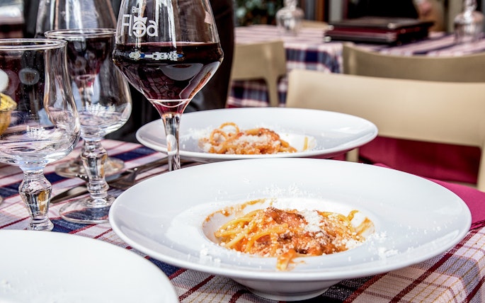 Italian pasta with tomato sauce and cheese served on a table with wine glasses in a restaurant.