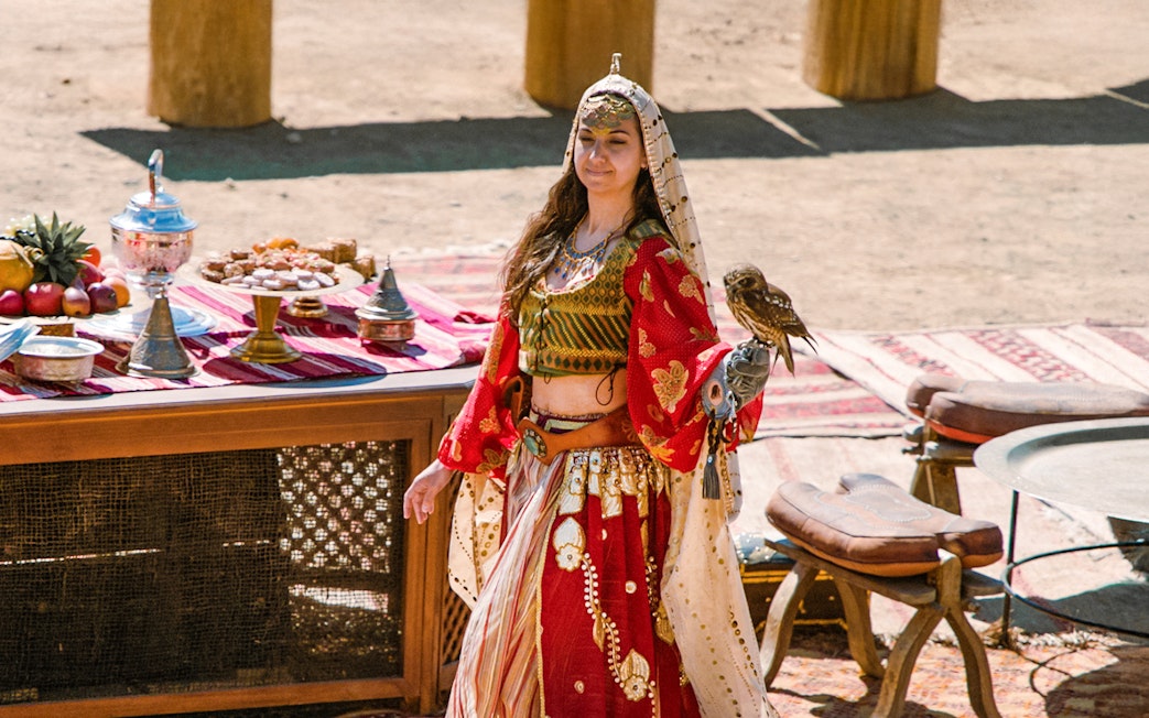 Performer with a bird at Puy du Fou España park, standing by a table with traditional items.