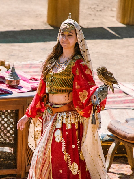 Performer with a bird at Puy du Fou España park, standing by a table with traditional items.