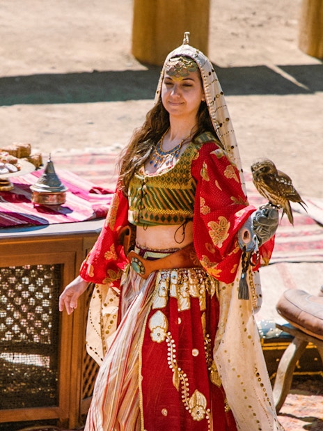 Performer with a bird at Puy du Fou España park, standing by a table with traditional items.
