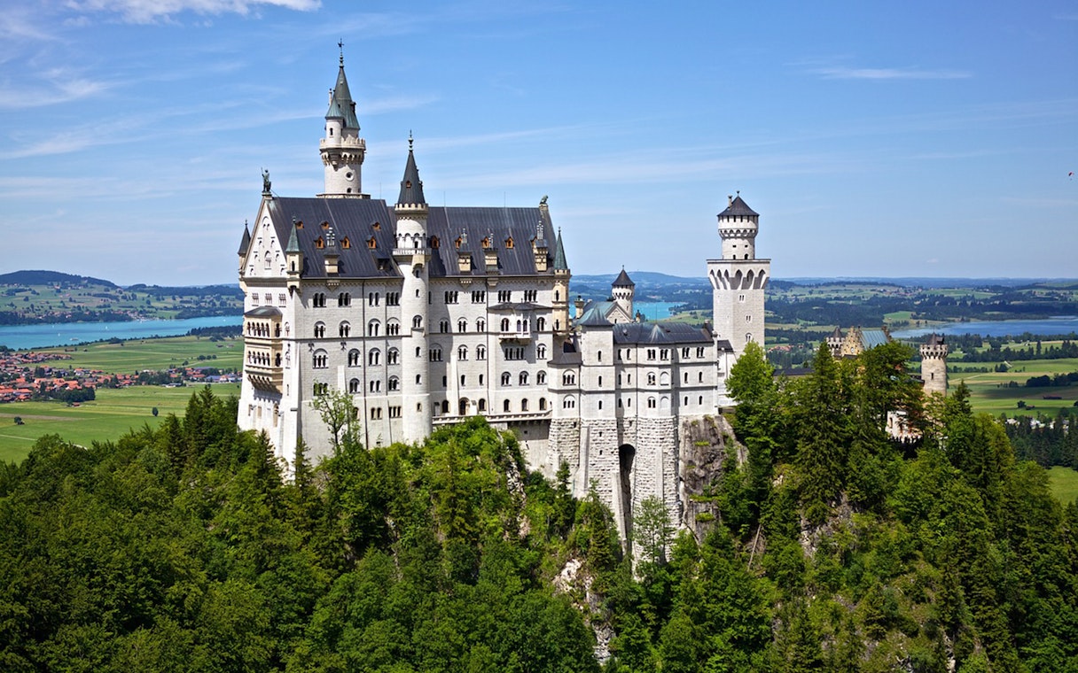 Neuschwanstein Castle surrounded by lush greenery, viewed on a day trip from Munich.