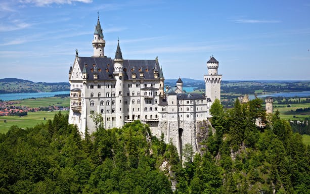 Neuschwanstein Castle surrounded by lush greenery, viewed on a day trip from Munich.