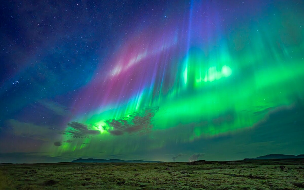 Northern lights over landscape during Premium Northern Lights Super Jeep Tour.