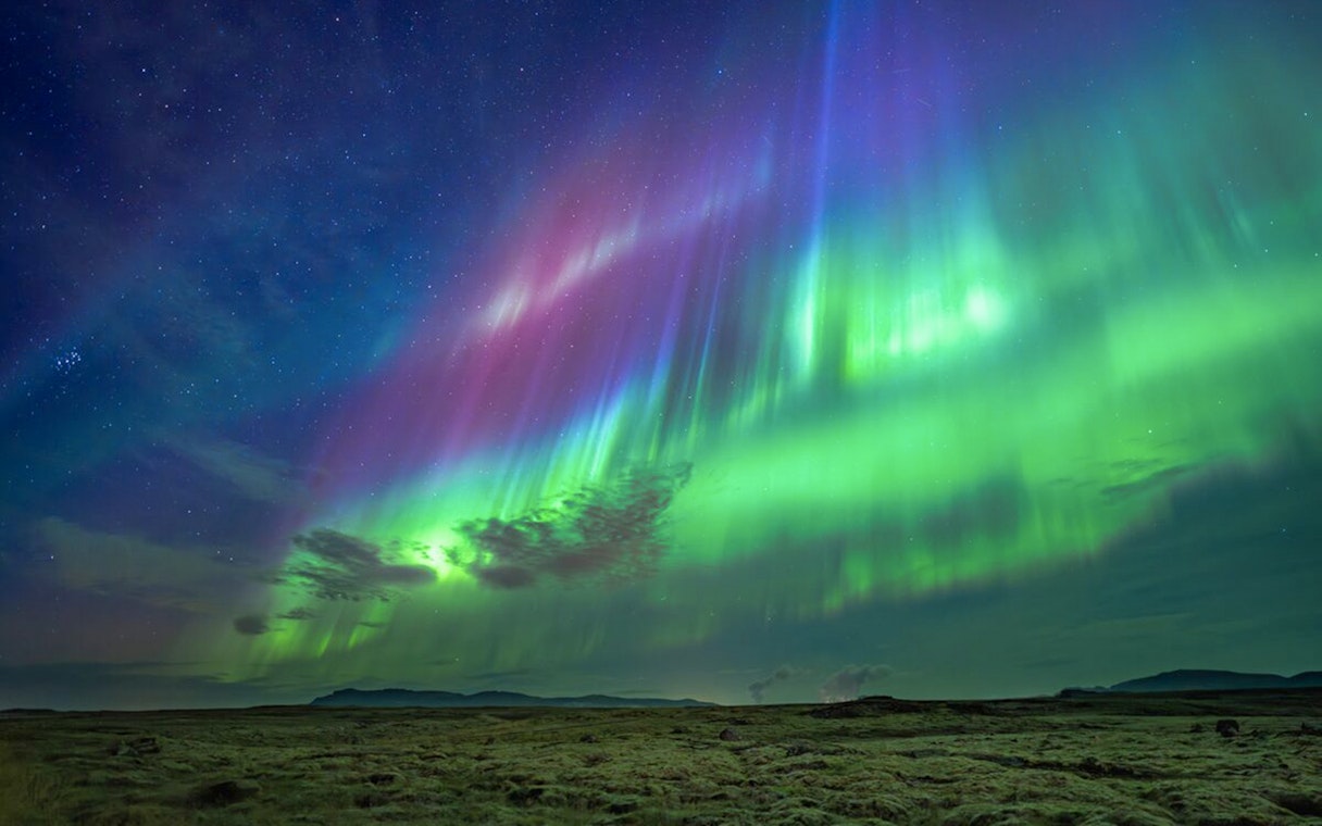 Northern lights over landscape during Premium Northern Lights Super Jeep Tour.