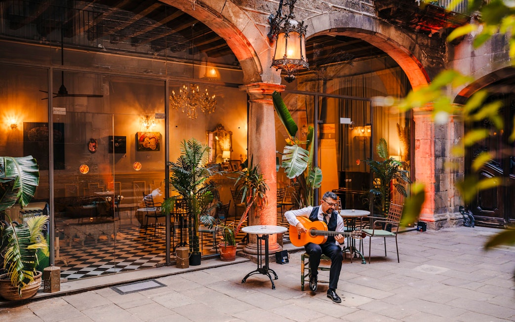 Guitarist performing at Palau Dalmases courtyard in Barcelona.
