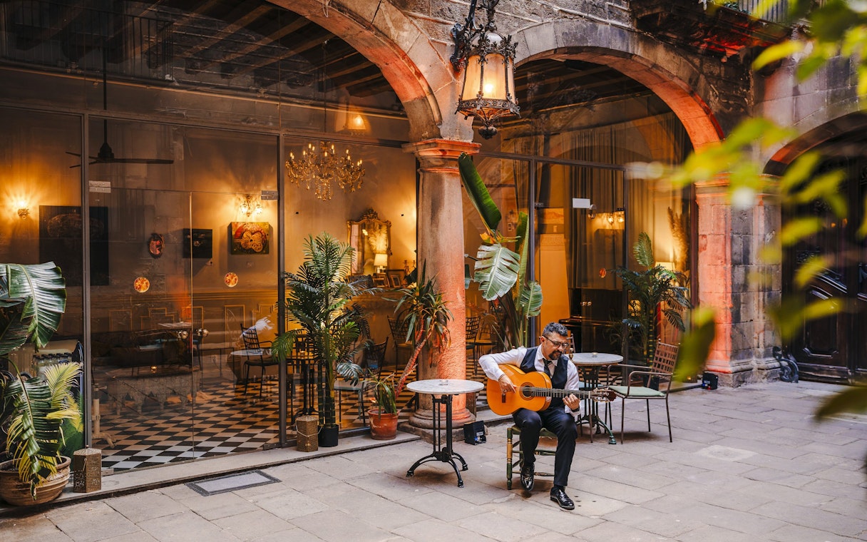 Guitarist performing at Palau Dalmases courtyard in Barcelona.
