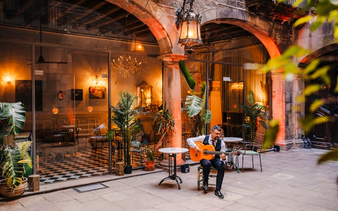 Guitarist performing at Palau Dalmases courtyard in Barcelona.