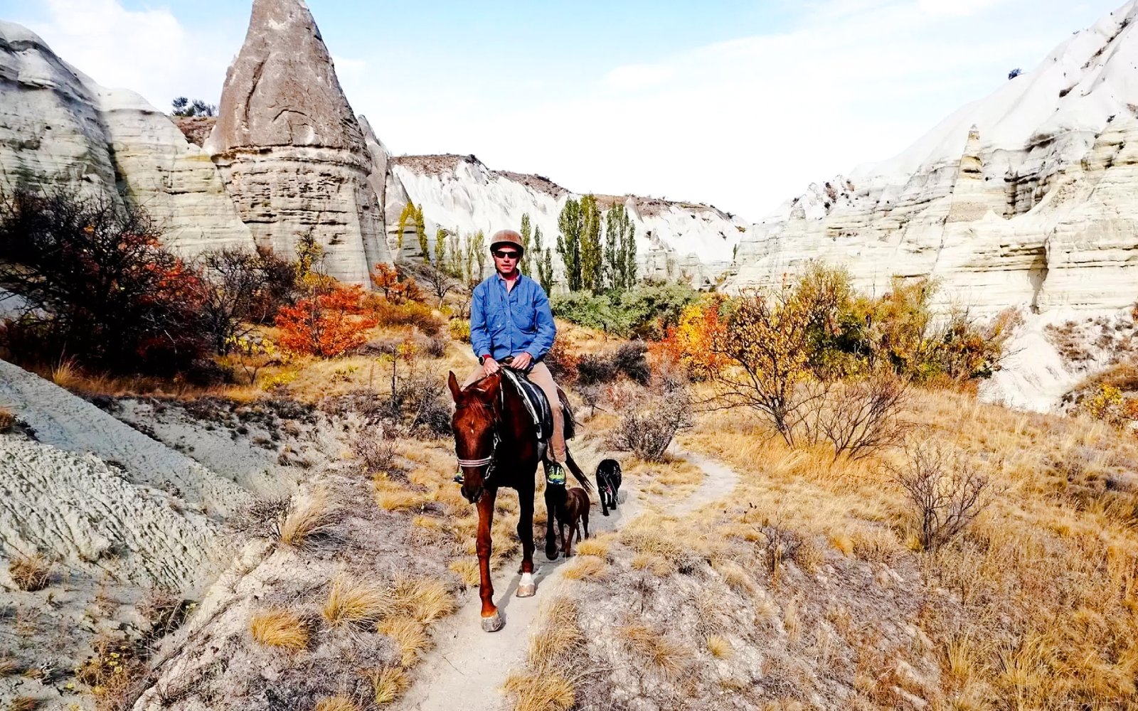 Horseback rider on a trail through Cappadocia's unique rock formations at sunset.