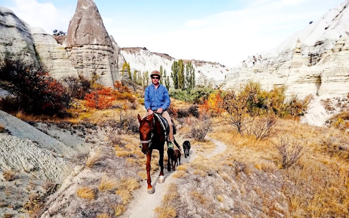 Horseback rider on a trail through Cappadocia's unique rock formations at sunset.