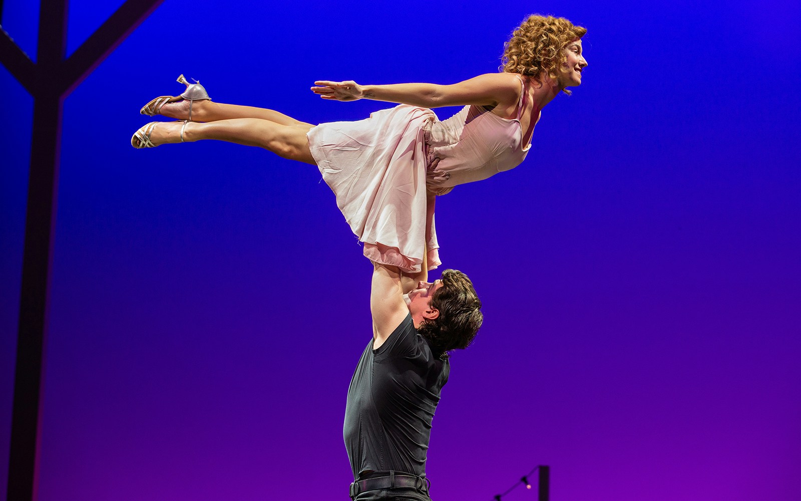 Man lifting woman in iconic dance pose from Dirty Dancing performance.
