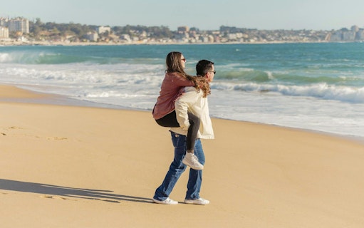 Tourists enjoying a walk on the sandy beach at Concón, Pacific Ocean in the background.