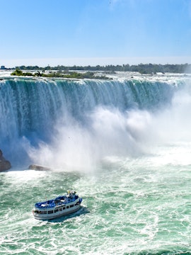 Boat tour approaching Niagara Falls, Canada, with mist rising from the waterfall.