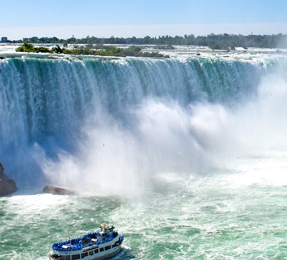 Boat tour approaching Niagara Falls, Canada, with mist rising from the waterfall.